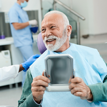 Man smiling holding dental mirror