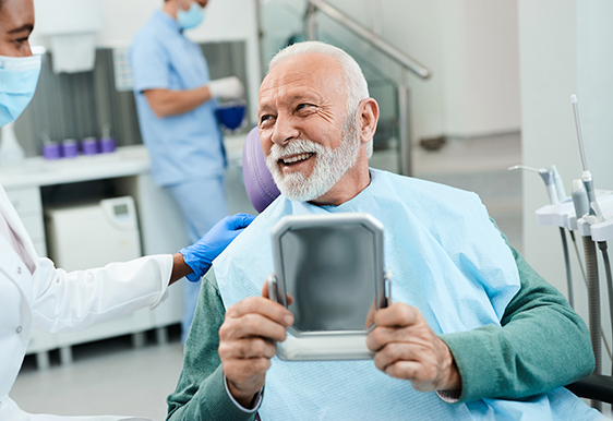 Man smiling holding dental mirror